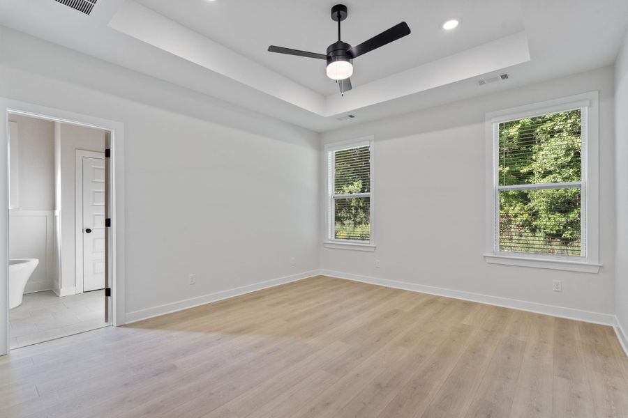Tray ceiling with recessed lighting, wood-finish flooring, and a ceiling fan