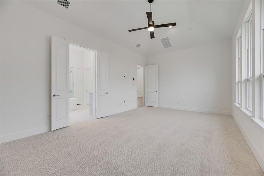Unfurnished bedroom with light carpet, ceiling fan, lofted ceiling, and ensuite bathroom