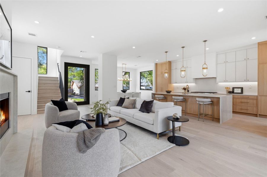 Living room featuring a warm lit fireplace, light wood-style floors, and recessed lighting