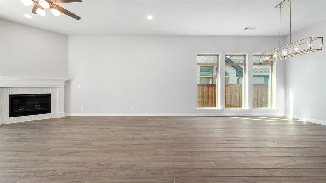 Unfurnished living room with a tiled fireplace, hardwood / wood-style flooring, and ceiling fan