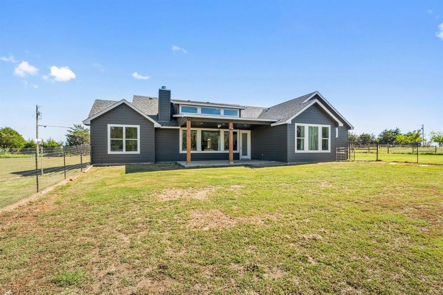 Rear view of property featuring a lawn and a patio area