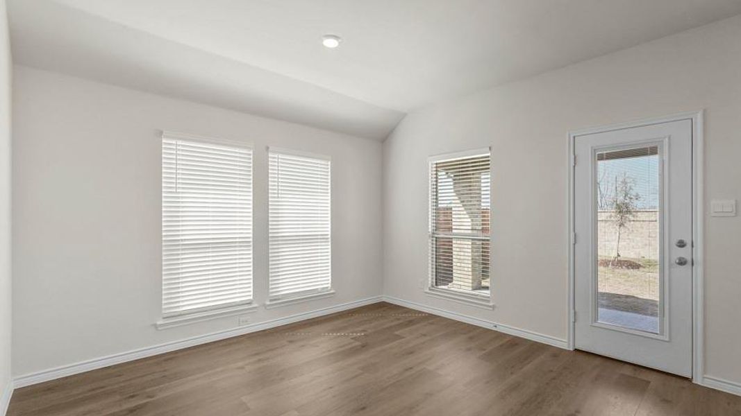 Spacious room featuring light-colored flooring, white walls, and multiple windows with blinds, providing views of the outdoor area