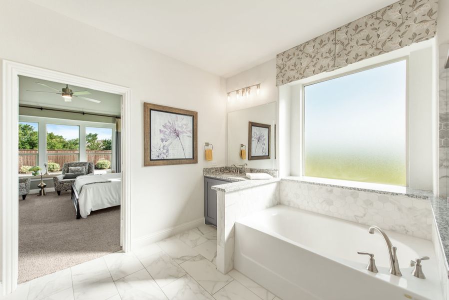 Master ensuite bathroom with soaking tub, granite vanity, marble tile floors, and open view into bedroom