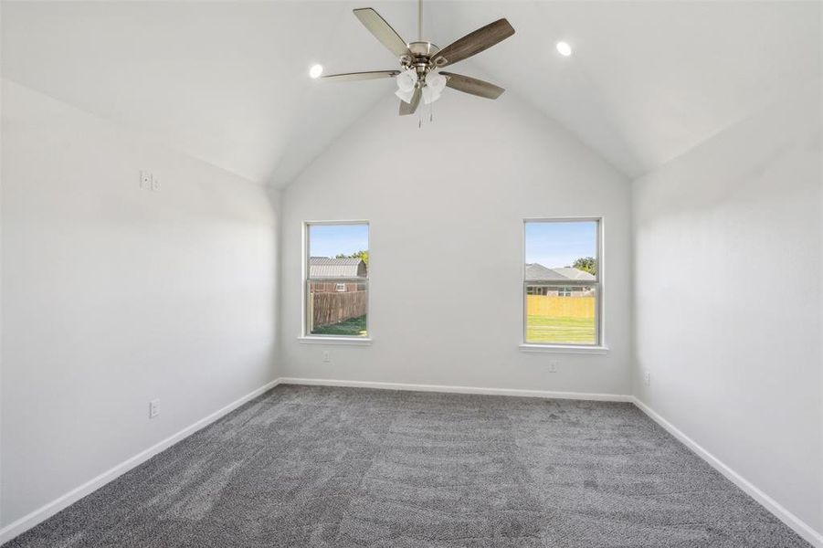 Spare room with carpet floors, ceiling fan, and lofted ceiling