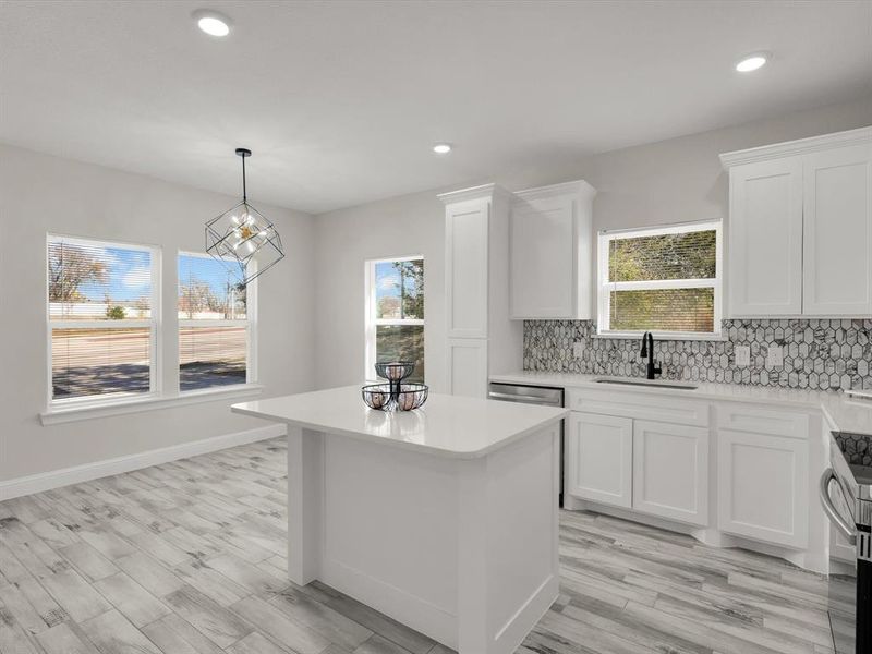 Kitchen with a center island, sink, hanging light fixtures, an inviting chandelier, and white cabinets