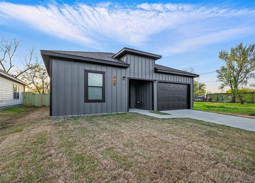 View of front of home with fence, a garage, concrete driveway, a front lawn, and board and batten siding View of front of home with fence, a garage, concrete driveway, a front lawn, and board and batten siding