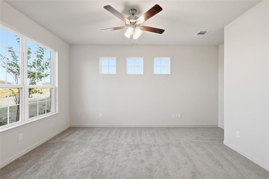 Spare room featuring light colored carpet and a ceiling fan