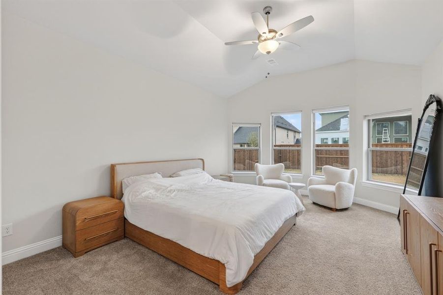 Bedroom with light colored carpet, vaulted ceiling, and a ceiling fan Bedroom with light colored carpet, vaulted ceiling, and a ceiling fan