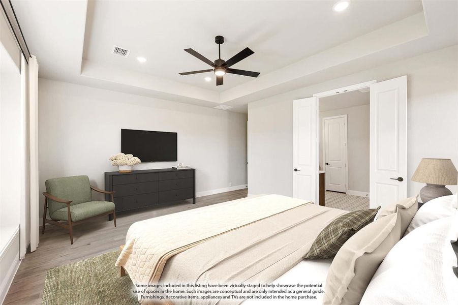 Bedroom with tray ceiling, ceiling fan, hardwood floors, and double doors leading to ensuite bathroom