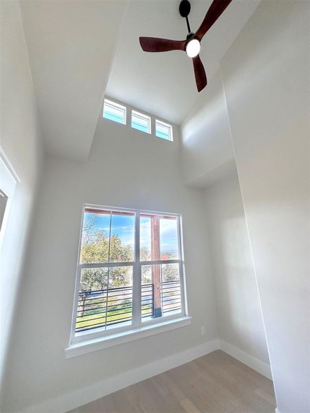 Office/Study room featuring a ceiling fan, light oak hardwood flooring, a towering ceiling, and plenty of natural light