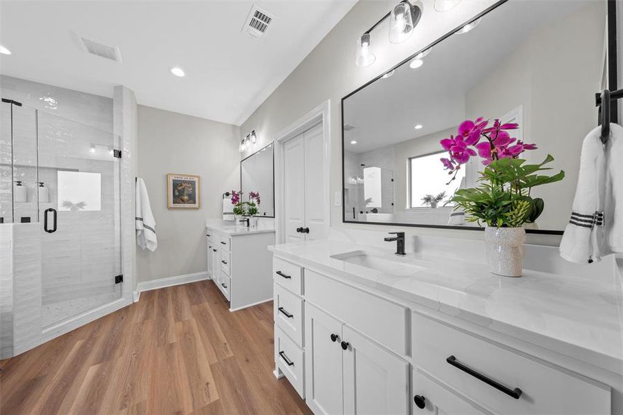 Full bath with light wood-style floors, two vanities, a shower stall, and recessed lighting Full bath with light wood-style floors, two vanities, a shower stall, and recessed lighting