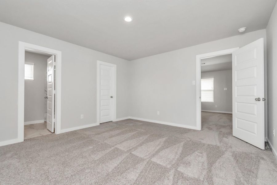 Generously sized secondary bedrooms, showcasing 5-panel doors with modern hardware, large windows adorned with privacy blinds, and spacious closets boasting sleek and contemporary finishes. Sample photo of completed home with similar floor plan. Actual colors and selections may vary.
