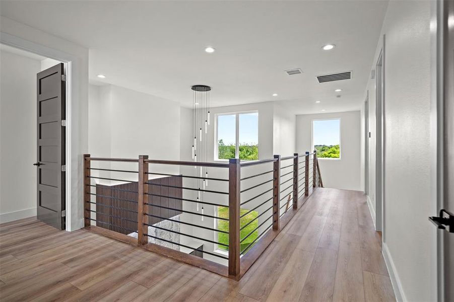 This landing area features hardwood flooring, white walls, and recessed lighting This landing area features hardwood flooring, white walls, and recessed lighting