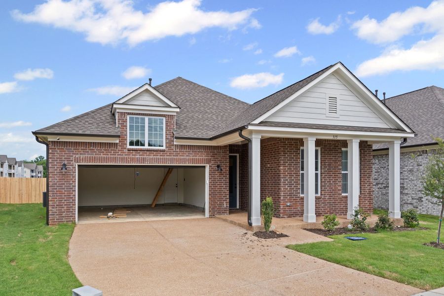 Brick exterior featuring a covered entry with white columns, an attached garage, and a dormer window above the garage Brick exterior featuring a covered entry with white columns, an attached garage, and a dormer window above the garage