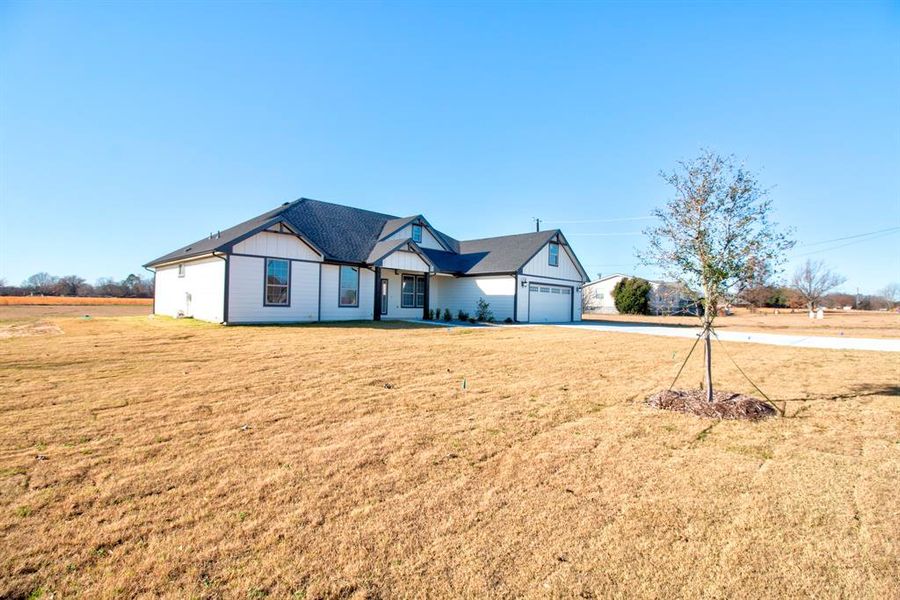 View of front of home with a front yard, covered porch, driveway, and a garage