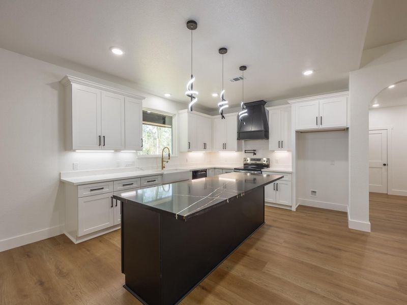 An abundance of cabinetry, deep drawers, and a walk-in pantry (not pictured) ensure this kitchen is as practical as it is beautiful. The black island with gold accents provides extra flair. An abundance of cabinetry, deep drawers, and a walk-in pantry (not pictured) ensure this kitchen is as practical as it is beautiful. The black island with gold accents provides extra flair.
