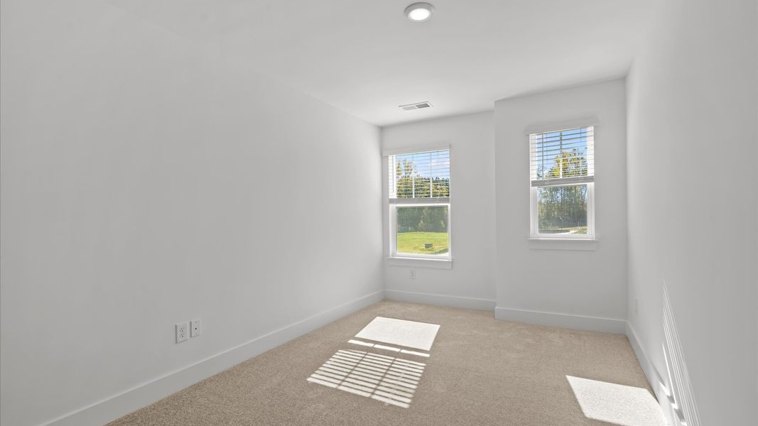 Elegant bedroom retreat featuring soft carpet and oversized windows that create a bright, welcoming space
