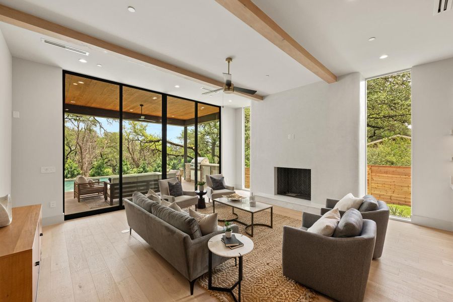 A spacious living room with hardwood floors offers an inviting atmosphere with a fireplace and large windows showcasing the natural outdoor landscape. A spacious living room with hardwood floors offers an inviting atmosphere with a fireplace and large windows showcasing the natural outdoor landscape.