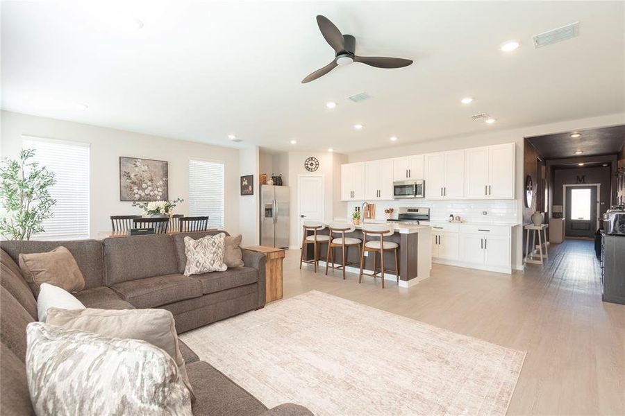 Open-concept living space featuring light wood-finish flooring, recessed lighting, and a contemporary ceiling fan Open-concept living space featuring light wood-finish flooring, recessed lighting, and a contemporary ceiling fan