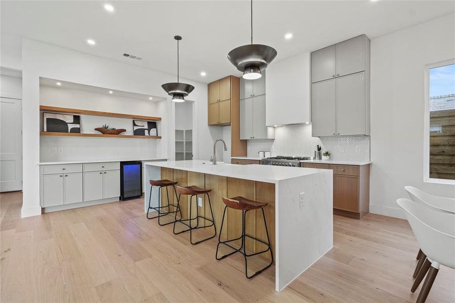 Kitchen with light stone countertops, light wood-type flooring, open shelves, tasteful backsplash, and recessed lighting