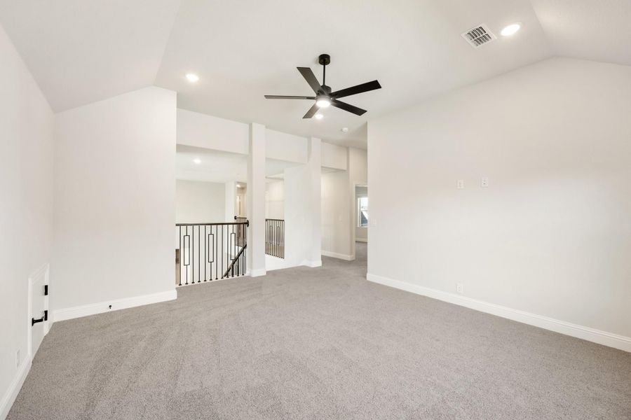 Upstairs bonus room with gray carpet, black ceiling fan, and open staircase railing