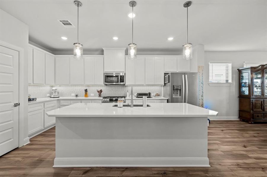 Kitchen with backsplash, white cabinetry, a kitchen island with sink, stainless steel appliances, and recessed lighting Kitchen with backsplash, white cabinetry, a kitchen island with sink, stainless steel appliances, and recessed lighting
