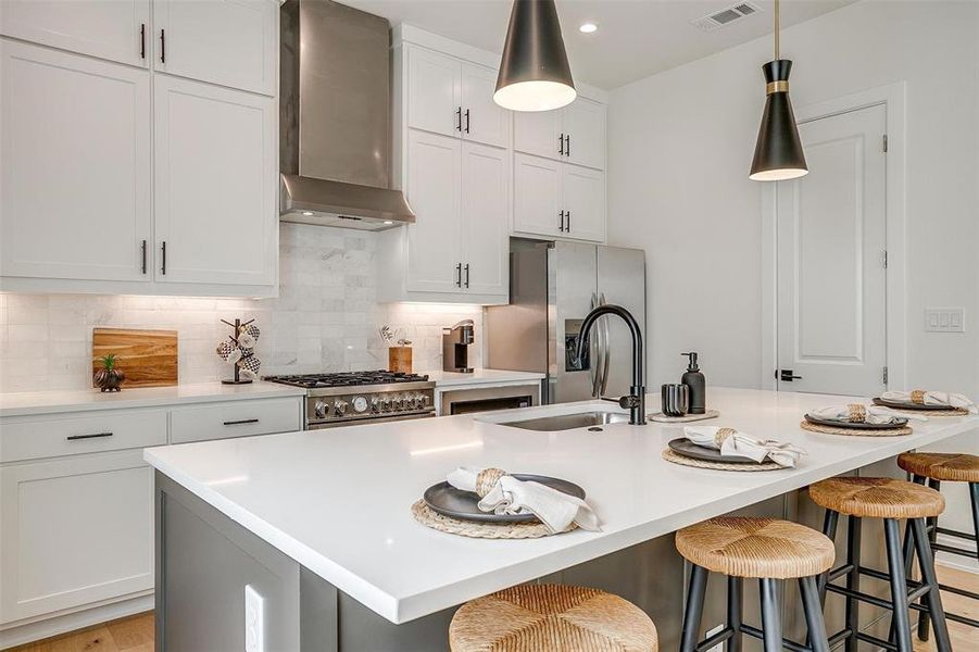 Kitchen featuring backsplash, wall chimney range hood, white cabinetry, and recessed lighting Kitchen featuring backsplash, wall chimney range hood, white cabinetry, and recessed lighting