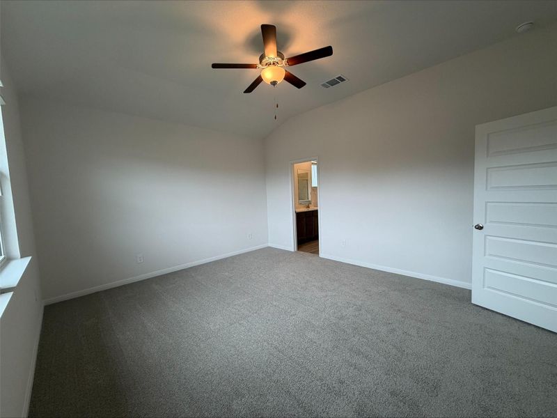 Unfurnished bedroom featuring lofted ceiling, ceiling fan, carpet, and ensuite bathroom