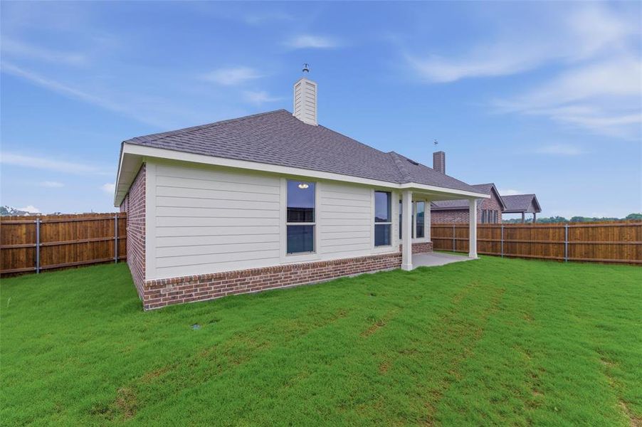Expansive backyard featuring a covered patio with columns, a privacy fence, and a brick and siding exterior