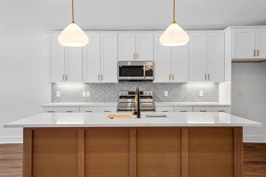 Kitchen with a sink, decorative backsplash, white cabinets, and stainless steel appliances