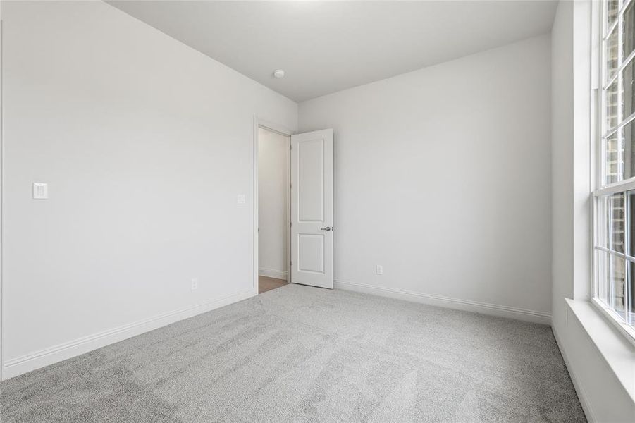 Empty room featuring light colored carpet and baseboards