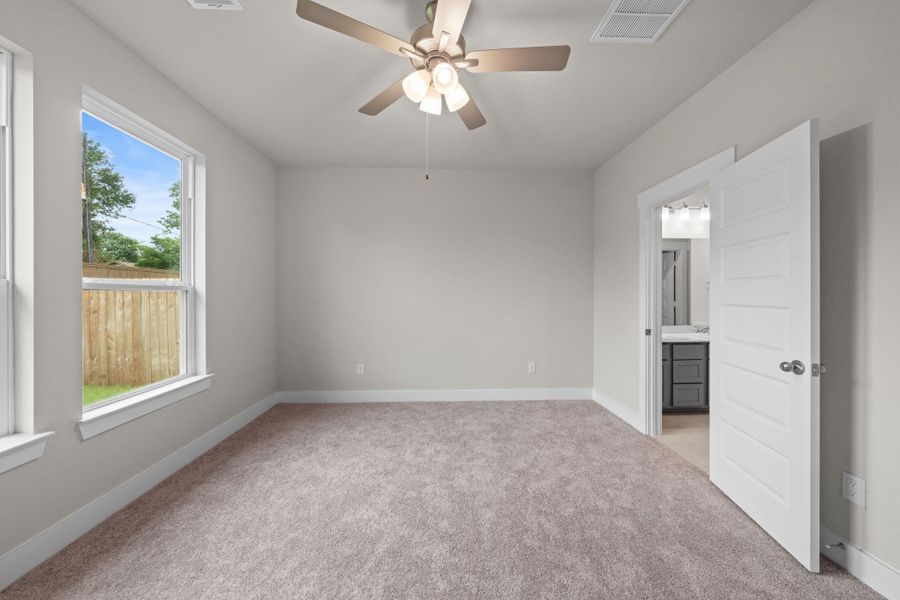 This beautifully designed primary suite, offering the perfect combination of comfort, style, and functionality. The spacious bedroom is filled with natural light from large windows that overlook the private backyard, while soft, neutral-toned carpeting adds a cozy touch.
