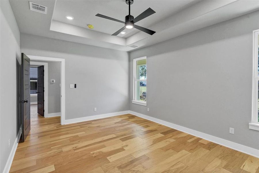 Spare room with light wood-style flooring, recessed lighting, a ceiling fan, and a raised ceiling