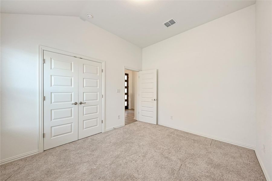 A spacious, naturally illuminated room featuring warm carpet flooring and multiple paneled doors.