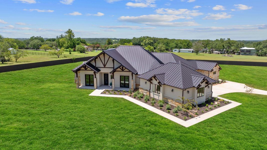 View of front of home featuring stucco siding, a standing seam roof, stone siding, a front yard, and a metal roof