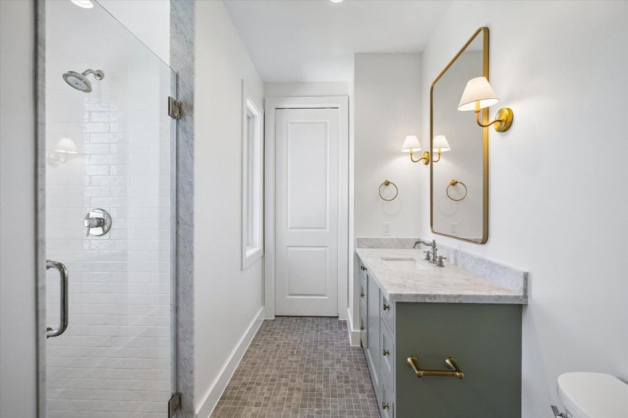 Secondary bath pairs a marble topped vanity in soft sage with warm brass fixtures and an oversized framed mirror for a tailored finish. Subway tile shower with marble trim and mosaic flooring adds classic texture with a fresh, modern edge.**PREVIOUS BUILDER WORK** Secondary bath pairs a marble topped vanity in soft sage with warm brass fixtures and an oversized framed mirror for a tailored finish. Subway tile shower with marble trim and mosaic flooring adds classic texture with a fresh, modern edge.**PREVIOUS BUILDER WORK**