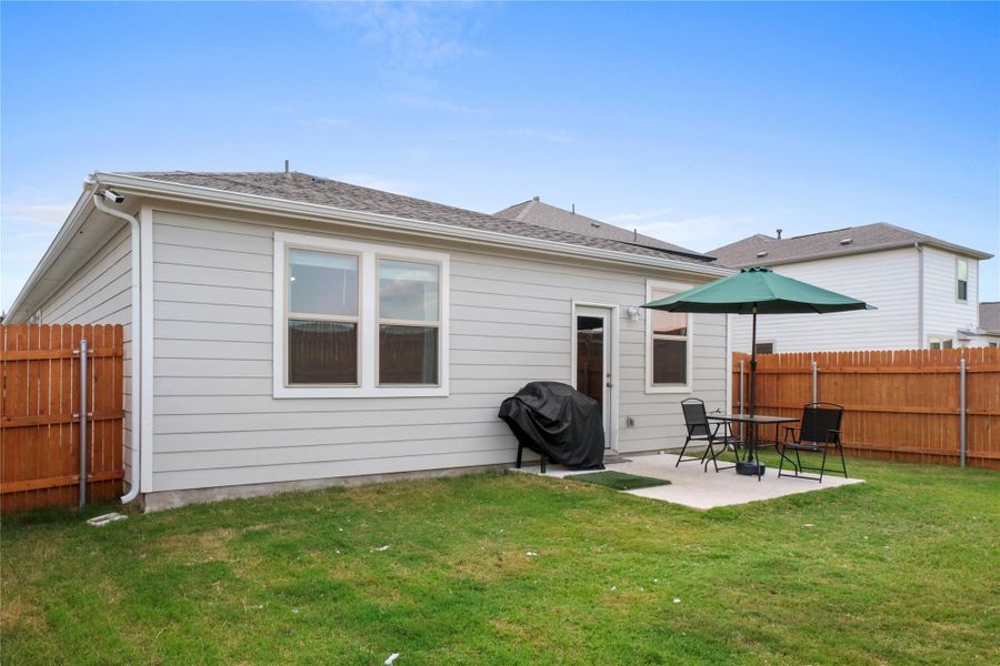 Back of property featuring a fenced backyard, a patio area, and a shingled roof
