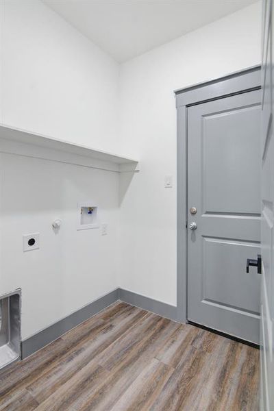 Laundry area featuring wood-finish flooring, white walls, and a built-in shelf