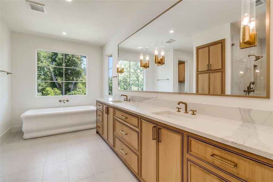 Full bath featuring a freestanding bath, double vanity, light tile patterned flooring, a chandelier, and tiled shower Full bath featuring a freestanding bath, double vanity, light tile patterned flooring, a chandelier, and tiled shower