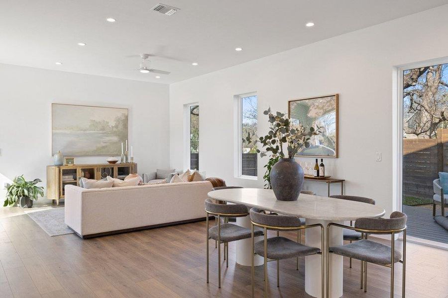 Dining room featuring recessed lighting with dimmers along with a wood panel wall with hidden door and under stair storage closet