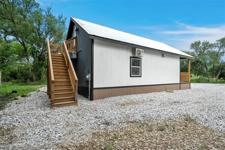 View of property exterior with stairs, a metal roof, a deck, and a wall unit AC View of property exterior with stairs, a metal roof, a deck, and a wall unit AC