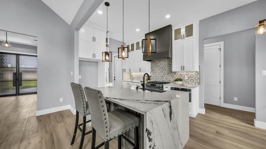 Kitchen featuring a breakfast bar, white cabinets, glass insert cabinets, backsplash, and light stone countertops