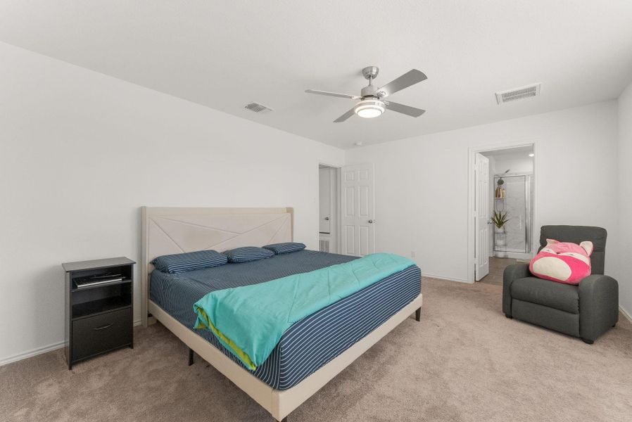 Carpeted bedroom with visible vents, ceiling fan, and baseboards