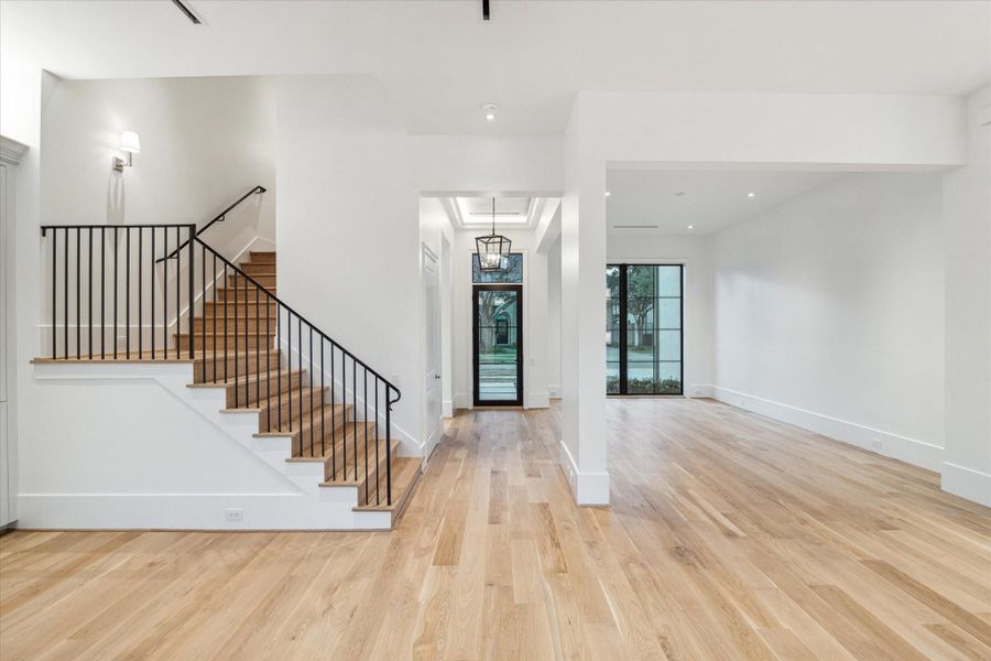 [Living / Dining Rooms]This view travels from the living room past the staircase to the dining room and foyer. Note white oak hardwood floor and staircase treads and risers.