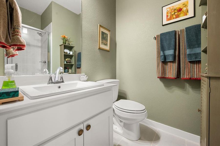 Bathroom featuring a textured wall, vanity, a shower stall, and tile patterned floors Bathroom featuring a textured wall, vanity, a shower stall, and tile patterned floors