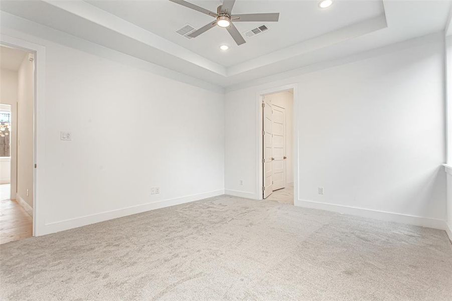 Unfurnished room with recessed lighting, light carpet, a ceiling fan, a tray ceiling, and baseboards