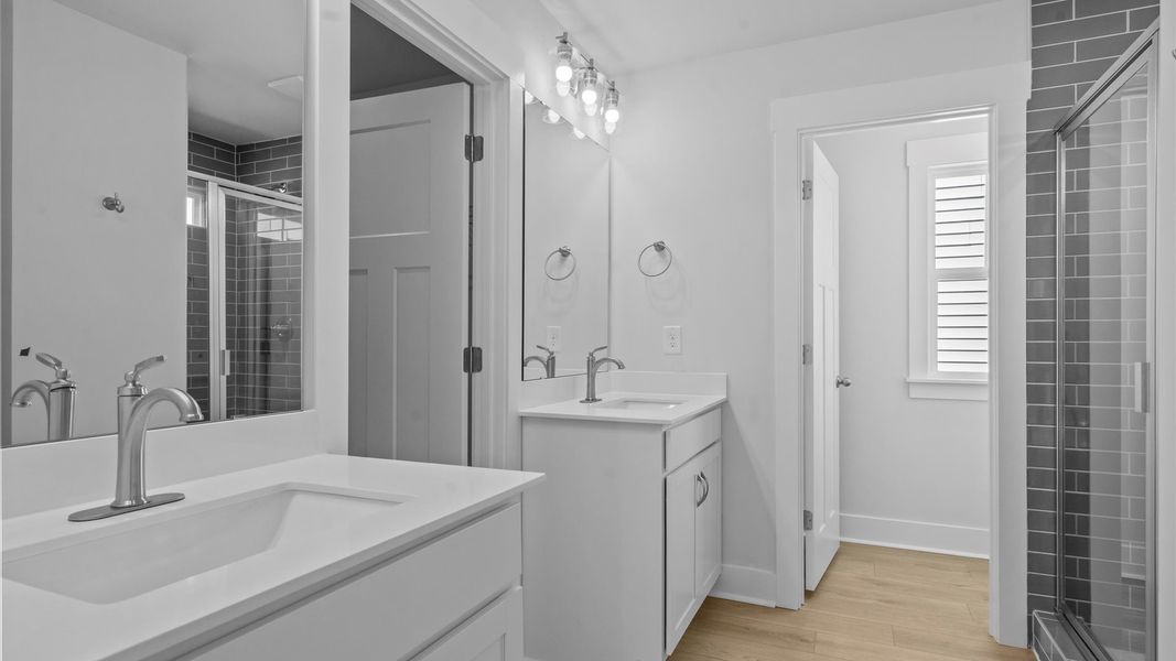 Highly functional and elegant en-suite with dual vanities, tiled walk-in shower, and refined finishes