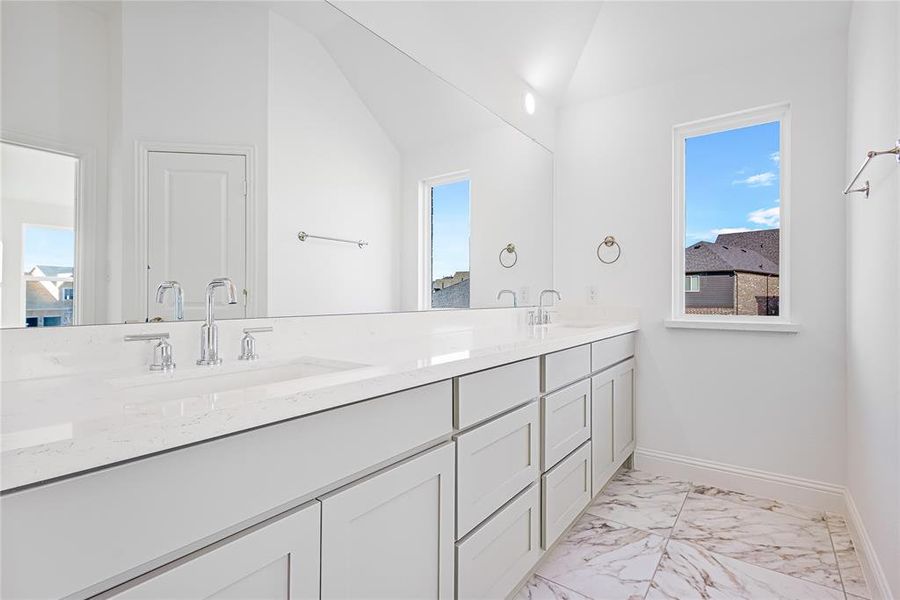 Bathroom featuring plenty of natural light, vaulted ceiling, and vanity