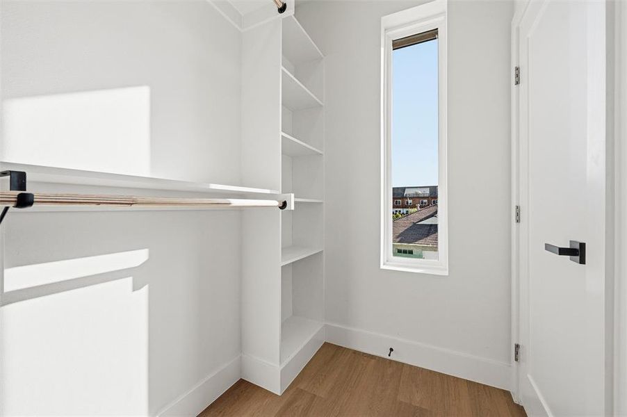 Walk-In Closet features built-in shelving with multiple storage tiers. Hanging rod extends along the adjacent wall. Window provides natural light throughout the space. Vinyl flooring extends throughout.