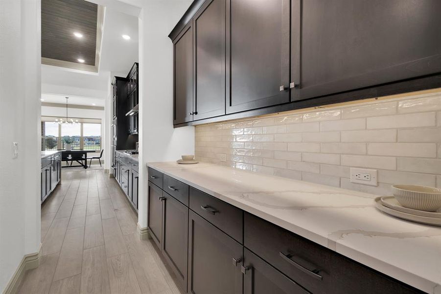 Kitchen with recessed lighting, a chandelier, backsplash, light stone counters, and light wood-style floors